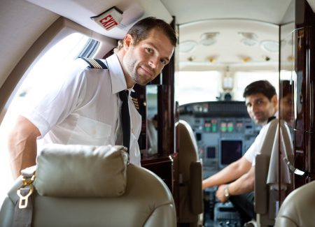 Portrait of handsome pilot entering private jet with copilot in background